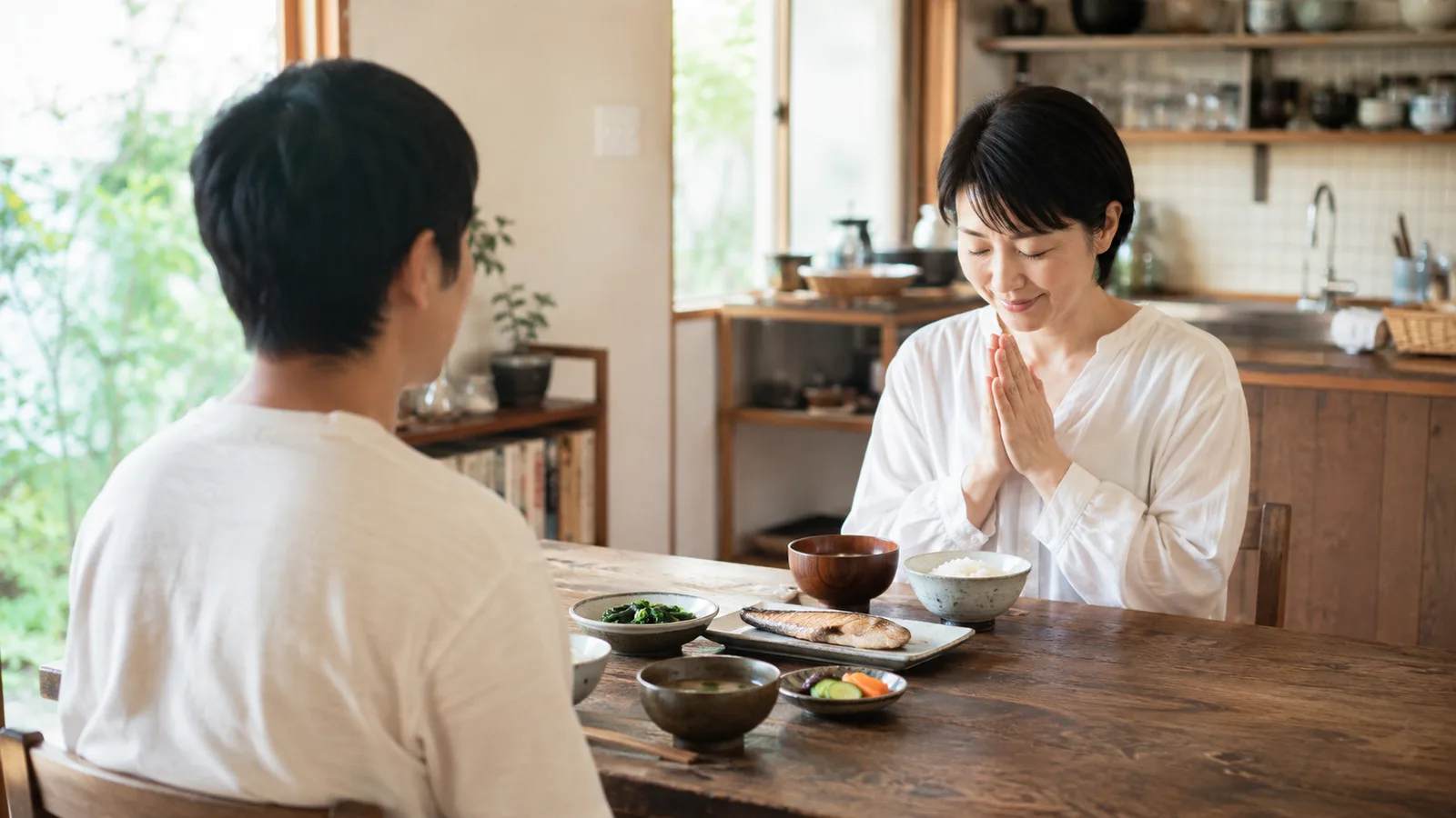 一對日本夫妻坐在餐桌前合掌說「我開動了」